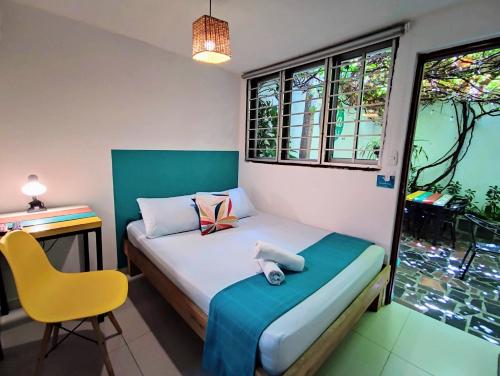 a small bedroom with a bed and a yellow chair at Bona Vida Hotel in Ríohacha