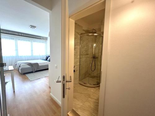 a bathroom with a shower and a bedroom with a bed at Modern Studio near Lugano's Lake & City Center in Lugano