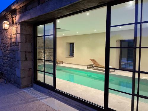 uma casa com uma piscina vista através das janelas em Les Villas d Onalou Kergastel em Penvénan