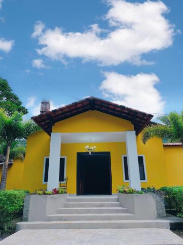 a yellow house with stairs in front of it at Hotel Boavista in Miguel Pereira