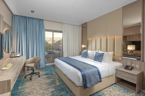 een hotelkamer met een groot bed en een bureau bij Seven Gardens Hotel in Riyad