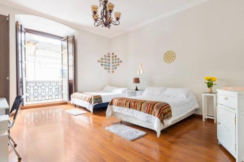 a white bedroom with two beds and a window at TRAVELER'S HOUSE QUITO in Quito