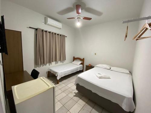 a bedroom with two beds and a ceiling fan at Hotel Sun City in Itápolis