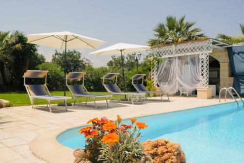 una piscina con sedie e ombrelloni accanto al resort di B&B Tenuta Martinelli a Monopoli