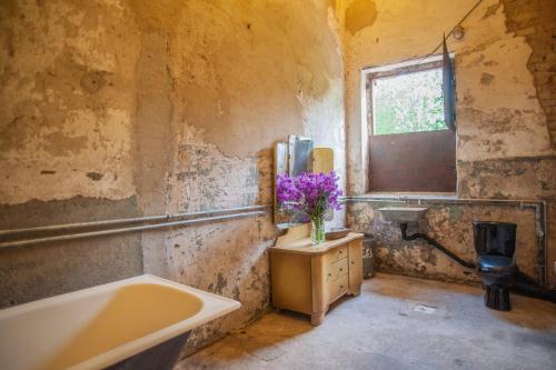 a bathroom with a sink and a tub and a vase of flowers at CAMP Agroturystyka Gorzelnia Gwieździn in Gwieździn