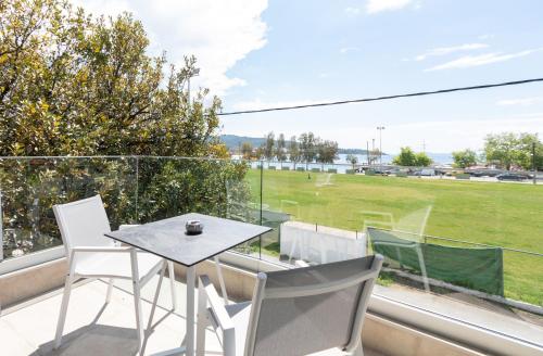 a table and chairs on a balcony with a view of a field at Thetis Boutique Apartments in Neos Marmaras