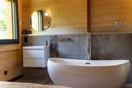 y baño con bañera blanca y lavamanos. en Chalet au coeur du Jura à 5min de la plage de Clairvaux, 