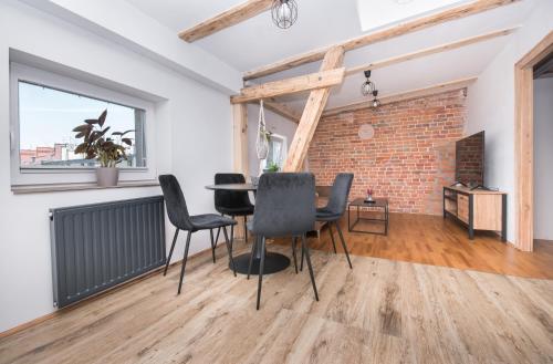 a room with a table and chairs and a brick wall at Apartament Nowy Świat 1 in Gliwice