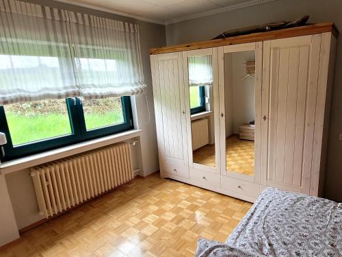 a bedroom with a large white cabinet and two windows at Wiesenhof in Orscholz