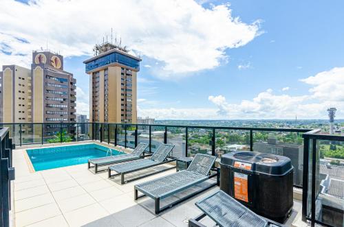 un balcón con piscina y sillas y un edificio en Studio incrível no condomínio clube sky Batel soho, en Curitiba