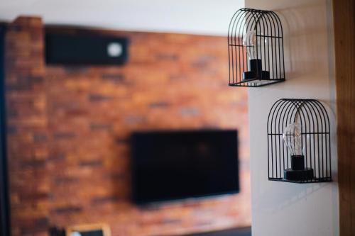 two bird cages hanging on a wall with a tv at Apartman PAOLA in Slavonski Brod