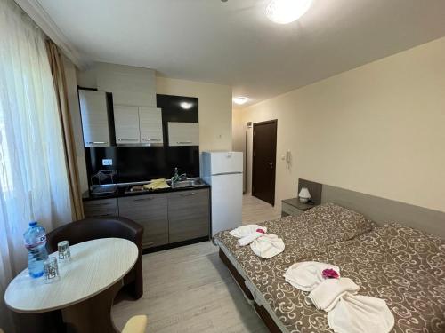 een kamer met een bed, een tafel en een keuken bij Brilliant Aparthotel in Sozopol
