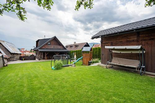 a yard with a house and a playground at Drevenica Emilka - Sprcha, Záhradná hojdačka, Ohnisko in Brezno