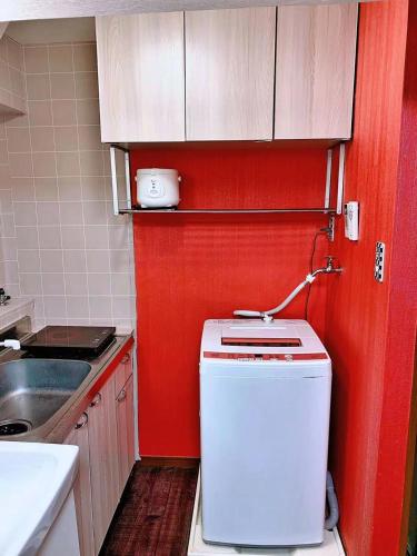 a small kitchen with red walls and a small refrigerator at Ueno上野!Akihabara秋葉原!Asakusa 浅草!3min walk to station!交通便利地点繁华!附近美食!商场百货遍地! 干湿分离! 智能马桶! 高速无限制网路! 高级公寓403 in Tokyo