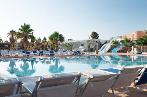 a swimming pool with chairs and a water slide at Camping Le Calypso 5 étoiles in Torreilles