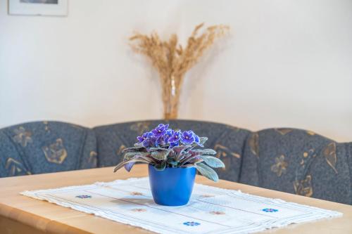 a blue vase with purple flowers on a table at Weingartnerhof Dalia in San Genesio Atesino