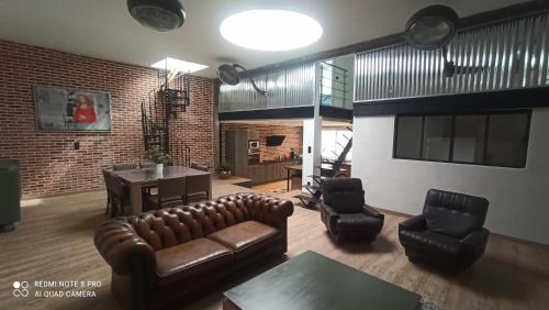 ein Wohnzimmer mit einem Ledersofa und Stühlen in der Unterkunft Loft 120m2 plein centre-ville de la Roche sur Yon in La Roche-sur-Yon