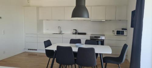 a white kitchen with a white table and chairs at Modern Spacious 3 Bedroom Apartment With Balcony At Richard Mortensens Vej Close To The Royal Arena And Fields in Copenhagen