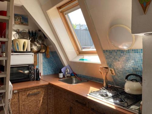 eine kleine Küche mit einem Waschbecken und einem Fenster in der Unterkunft Petite city center loft on Amstel river in Amsterdam