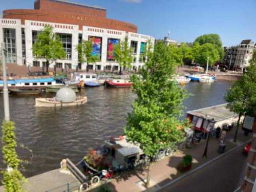 Blick auf einen Fluss mit Booten in einer Stadt in der Unterkunft Petite city center loft on Amstel river in Amsterdam