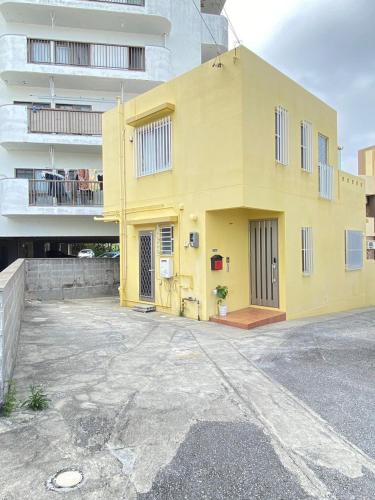 a yellow building in front of a building at いえろーはうす in Takahara
