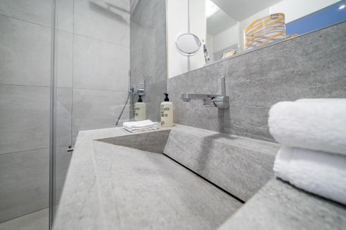 a bathroom with a sink and a shower with towels at bodenseezeit Apartmenthotel Garni in Lindau