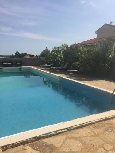 a large swimming pool with blue water at les olivades in Magalas