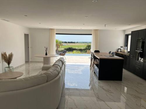 un salon avec un canapé et une table et une cuisine dans l'établissement Villa piscine à débordement, à Pignan