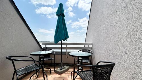 un balcon avec une table, des chaises et un parasol dans l'établissement Plein Sud, appartement vue baie, accès direct plage, au Crotoy