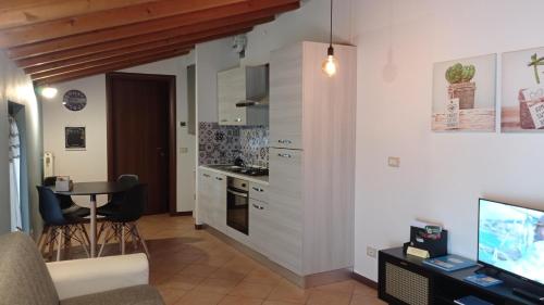 cocina y sala de estar con mesa y TV en Il Fante di Picche en Verolanuova