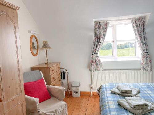 1 dormitorio con 1 cama, 1 silla y 1 ventana en Coninbeg Holiday Cottage by Trident Holiday Homes en Kilmore Quay