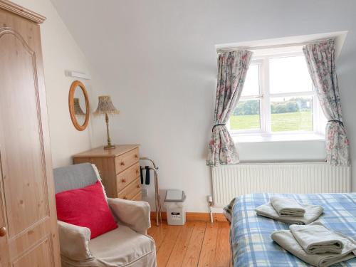 ein Schlafzimmer mit einem Bett und einem Stuhl und einem Fenster in der Unterkunft Coninbeg Holiday Cottage by Trident Holiday Homes in Kilmore Quay