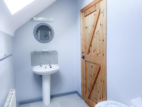 ein Badezimmer mit Waschbecken und Holztür in der Unterkunft Coninbeg Holiday Cottage by Trident Holiday Homes in Kilmore Quay