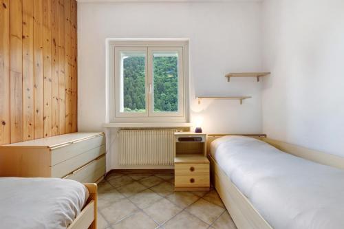 2 Betten in einem kleinen Zimmer mit Fenster in der Unterkunft Casa Nova in Dare