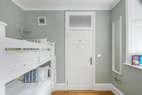 a bedroom with white bunk beds and a white door at 1 The Old Signal House, Penlee Point in Torpoint