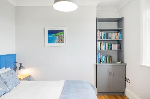 a bedroom with a bed and a book shelf at 1 The Old Signal House, Penlee Point in Torpoint