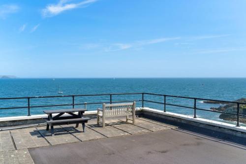 a bench and picnic table on a pier overlooking the ocean at 1 The Old Signal House, Penlee Point in Torpoint