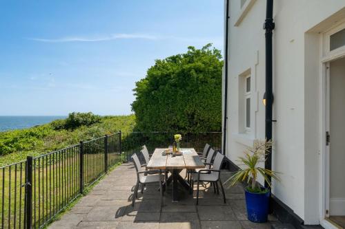a table and chairs on a balcony with the ocean at 1 The Old Signal House, Penlee Point in Torpoint