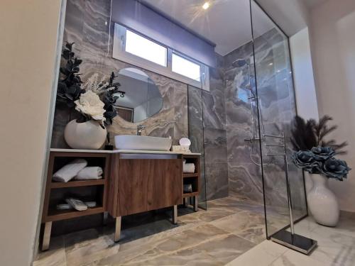 Luxury Apartment Olea Afandou في أفانتو: حمام مع حوض ودش زجاجي