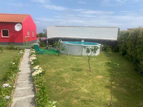 un patio trasero con piscina y una casa roja en Quinta do Norte - Biscoitos en Angra do Heroísmo