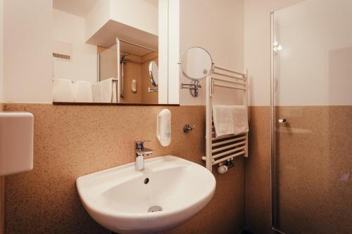 a bathroom with a sink and a mirror and a shower at Hotel Adler in Eichstätt