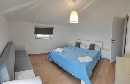 een slaapkamer met een blauw bed en een bank bij G&G Holidays in Santa Maria di Castellabate