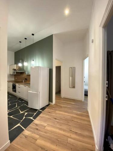 Il comprend une cuisine équipée d'un réfrigérateur blanc et du parquet. dans l'établissement Béziers - Appartement 3 chambres Parking privee -WIFI -Clim, à Béziers
