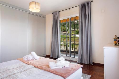 a bedroom with two towels on a bed in front of a window at Apartamento Maria in Canhas