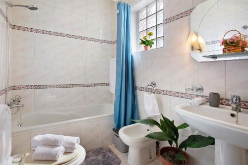een badkamer met een bad, een toilet en een wastafel bij Apartamento Maria in Canhas
