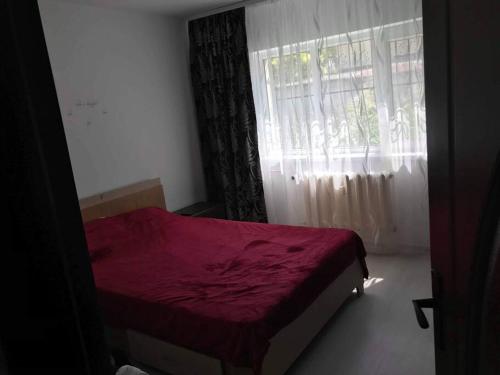um quarto com uma cama vermelha e uma janela em Locatie buna la 2-3 min de plaja em Mangalia