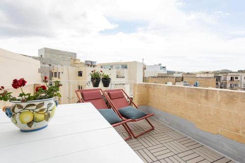 a balcony with a table and chairs on a roof at Little Blue House in Marsalforn