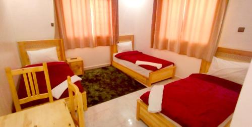 a room with three beds with red sheets at Hotel Assafa in Dakhla