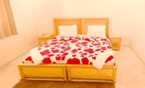ein Schlafzimmer mit einem Bett mit roten Blumen darauf in der Unterkunft Hotel Assafa in Ad-Dakhla