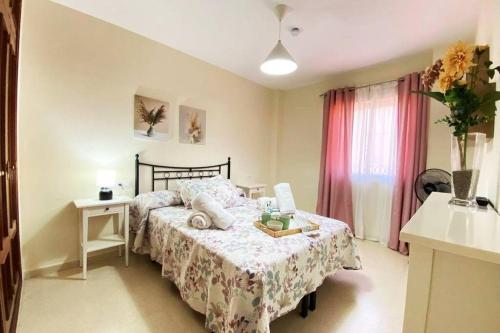 Un dormitorio con una cama y una mesa y una ventana. en Apartamento Camaleón, en Chipiona